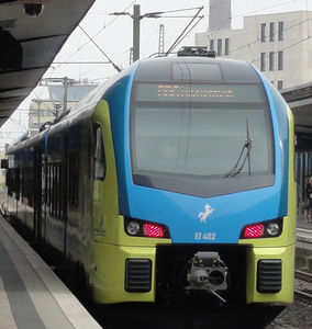 Moderner gelb-blauer Zug der Westfalenbahn von vorne am Bahnsteig