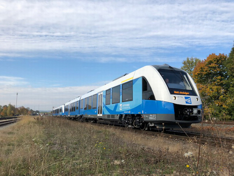 Moderner hellblau-weißer Zug der Bentheimer Eisenbahn von links nach rechts fahrend