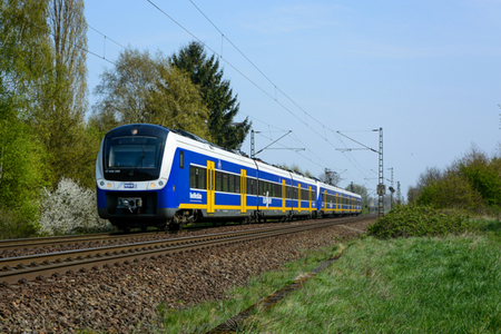 Weiß-blau-gelber Zug der NordWestBahn nach links fahrend