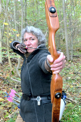 Susanne Wecken konzentriert am Bogen in einer Waldlandschaft