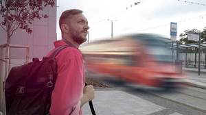 Bärtiger Fußgänger mit Rucksack mit verwischtem rotem öffentlichen Fahrzeug in Bewegung im Hintergrund