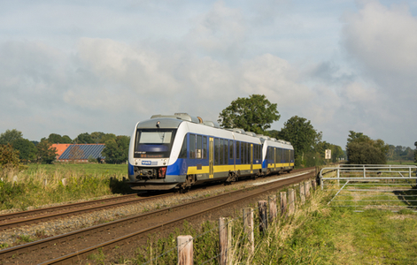 Weiß-blau-gelber Zug der NordWestBahn nach links fahrend