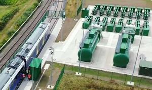 Luftaufnahme der Wasserstoff-Tankstelle bei Bremervörde mit grünen Tanks und einem Zug auf dem Gleis davor