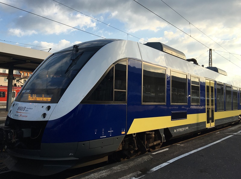Weiß-blau-gelber Zug der NordWestBahn am Bahnsteig